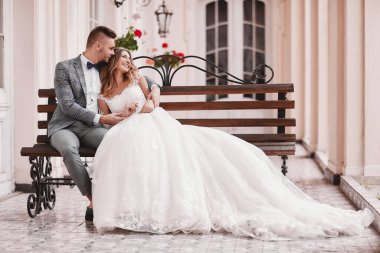 Düğün günü. Beyaz uzun elbiseli güzel gelin ve siyah takım elbiseli genç damat Avrupa 'nın tarihi şehrinde sarılıyorlar..