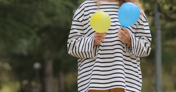 Vrouw met blauwe en gele luchtballonnen in de buitenlucht. Oekraïense meisje in gestreepte blouse met ballonnen kleuren van de vlag van Oekraïne — Stockvideo