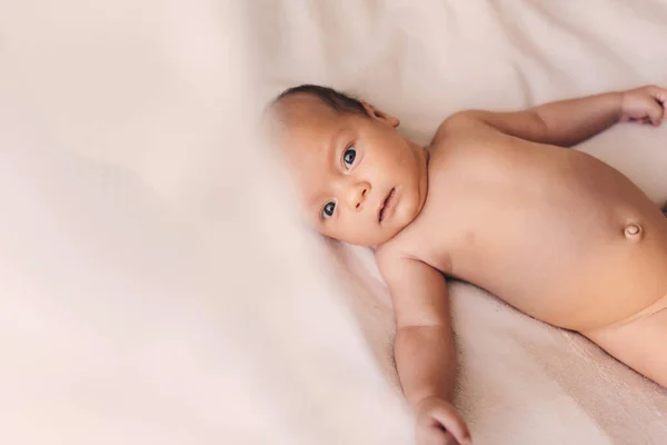 Soft picture of a beautiful baby laying on white bedding at home — Stock Photo, Image