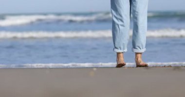 Güneşli bir günde kumsalda deniz kenarında çıplak ayakla dans eden bir kadın. Yüksek kalite 4k görüntü