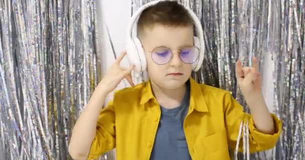 一个拿着大的白色耳机 积极地跳舞和听音乐的欧洲小男孩 音乐的概念 家庭休闲 高质量的4K镜头 — 图库视频影像