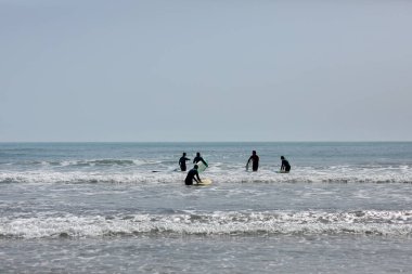 İspanya-Castellon, 16 Nisan 2022: Akdeniz 'de sörf tahtasında yüzmeyi öğrenen bir grup insan