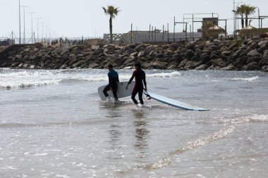 İspanya-Castellon, 16 Nisan 2022: Akdeniz 'de sörf tahtasında yüzmeyi öğrenen bir grup insan