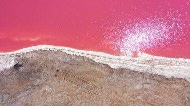 Pembe bir tuz gölünün üzerinde uçuyor. Tuz üretim tesisleri tuzlu göldeki tuz buharlaştırma göleti tarlaları. Dunaliella tuzlu kuru kristalize edilmiş tuzlu kıyılarla mineral gölüne kırmızı, pembe bir su döker.