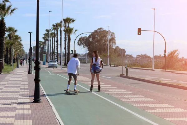 Tatil tatilleri. Patenli bir kadın ve kaykaylı bir adam güneşli yaz günlerinde dışarıda eğleniyorlar. Aşk ve arkadaşlık kavramı. Yüksek kalite fotoğraf