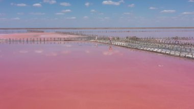 Pembe bir tuz gölünün üzerinde uçuyor. Tuz üretim tesisleri tuzlu göldeki tuz buharlaştırma göleti tarlaları. Dunaliella tuzlu kuru kristalize edilmiş tuzlu kıyılarla mineral gölüne kırmızı, pembe bir su döker.