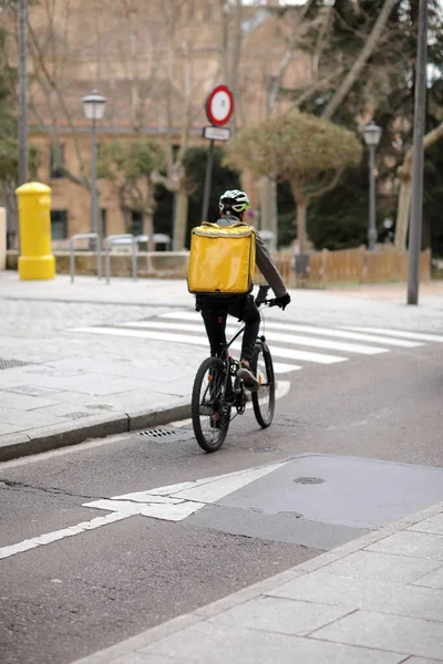 Food and grocery delivery. The bicycle courier, with a yellow thermo backpack, the food company, delivers necessary goods to residents of the city — Foto de Stock