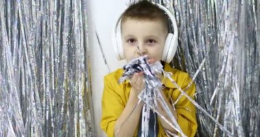 Büyük beyaz kulaklıklı küçük Avrupalı bir çocuk aktif olarak dans ediyor ve müzik dinliyor. Müzik konsepti, ev eğlencesi. Yüksek kalite 4k görüntü