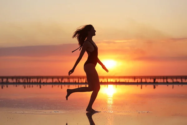 一个穿着泳衣 在日落时在海里跳舞的瘦小女子的肖像 — 图库照片