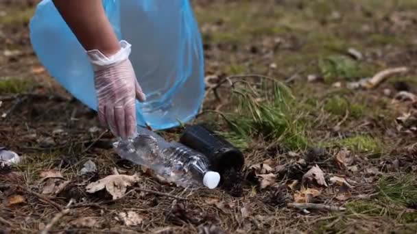 Clean up day. Cropped shot of a woman volunteer wearing gloves with trash bag in hands cleaning forest or park from garbage. Ecology problems and nature pollution. High quality 4k footage — Wideo stockowe