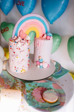 Gökkuşaklı büyük doğum günü pastası, renkli serpintiler. Bir çok renkli kalp balonunun arka planında. Doğum günü partisi. Güzel tatil.