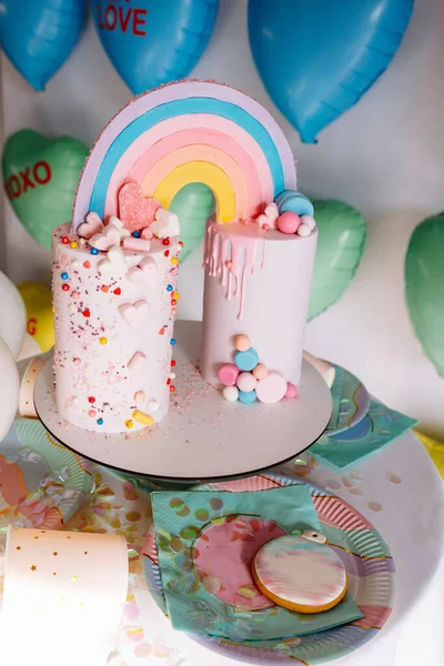Gökkuşaklı büyük doğum günü pastası, renkli serpintiler. Bir çok renkli kalp balonunun arka planında. Doğum günü partisi. Güzel tatil.