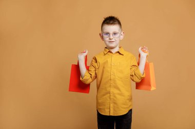 Kara Cuma 'da alışveriş. Sarı arka planda alışveriş torbaları tutan küçük bir çocuk. Bir sürü renkli kağıt torbası olan bir müşteri. Tatil satışları ve indirimler. Siber pazartesi. Yüksek kalite fotoğraf.