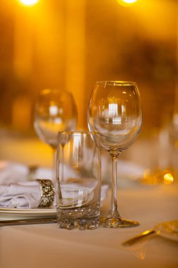 Restoranda boş cam seti. düğün, dekor, kutlama, tatil konsepti - beyaz masa örtülü romantik masa örtüsü, tabak, kristal gözlük.