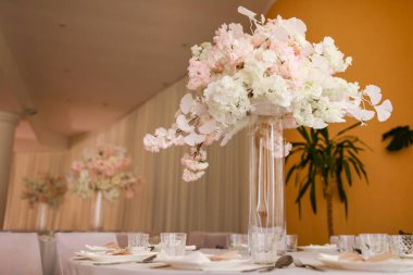 Şenlikli düğün dekorasyonu. Düğün günü yemek masasında cam vazoda duran güzel, beyaz ve pembe çiçekler. Yüksek kalite fotoğraf.