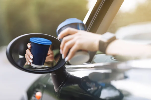 cropped photo of woman\'s hand holding blue paper cup of coffee in car. Hot drink take away. Travel with coffee. Concept of coffee with you. Mockup.