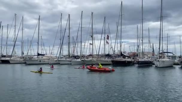CASTELLON, SPAIN - 1 MAY 2022: group of Kids at summer camp swimming on canoe on the sea with instructor on boat. Port of the town. — Stock Video