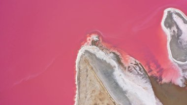 Pembe bir tuz gölünün üzerinde uçuyor. Tuz üretim tesisleri tuzlu göldeki tuz buharlaştırma göleti tarlaları. Dunaliella tuzlu kuru kristalize edilmiş tuzlu kıyılarla mineral gölüne kırmızı, pembe bir su döker.