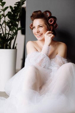 Uzun beyaz dantelli ve pembe bukleli parlak makyajlı, gösterişli, genç bir esmer kadın. Güzellik konsepti Uluslararası Kadınlar Günü.