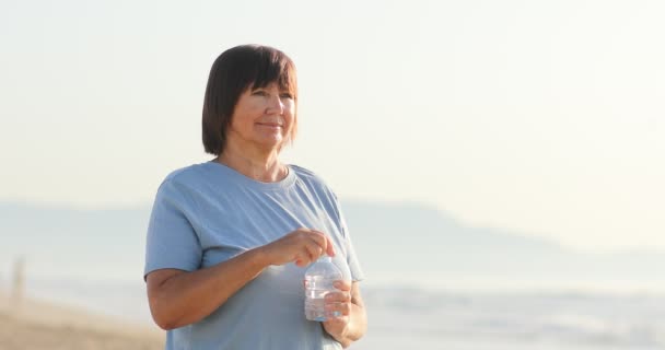 Mulher Sorridente Beber Água Garrafa Plástico Junto Mar Dia Ensolarado — Vídeo de Stock