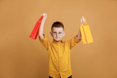 Kara Cuma 'da alışveriş. Sarı arka planda alışveriş torbaları tutan küçük bir çocuk. Bir sürü renkli kağıt torbası olan bir müşteri. Tatil satışları ve indirimler. Siber pazartesi. Yüksek kalite fotoğraf.