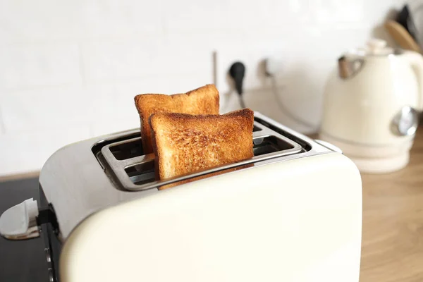 toasted grain bread in white toaster, roasted sandwich toast, concept of healthy eating, dieting, snacking at work, at school, student fast food. Modern white toaster