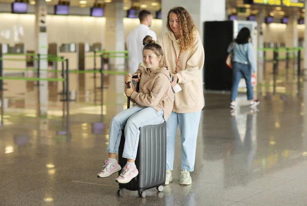방학에 긍정적 미소를 소녀의 가방에 앉아서 터미널 공항에 즐거움을 엄마는 — 스톡 사진