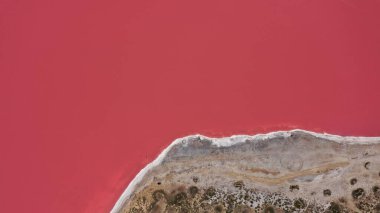 Pembe bir tuz gölünün üzerinde uçuyor. Tuz üretim tesisleri tuzlu göldeki tuz buharlaştırma göleti tarlaları. Dunaliella tuzlu kuru kristalize edilmiş tuzlu kıyılarla mineral gölüne kırmızı, pembe bir su döker.
