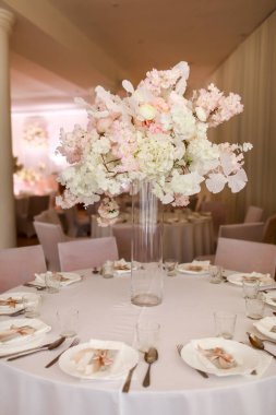 Şenlikli düğün dekorasyonu. Düğün günü yemek masasında cam vazoda duran güzel, beyaz ve pembe çiçekler. Yüksek kalite fotoğraf.