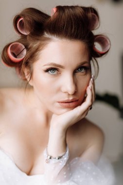 Güzellik konsepti Pembe bukleli parlak makyajlı, gösterişli, genç bir esmer kadının portresi. Stüdyo Çekimi, Kırpılmış. Yüz bakımı. Kozmetoloji, cilt bakımı ve kaplıca.