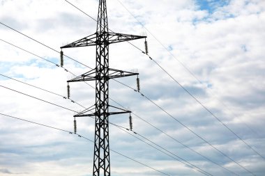 Mavi arka planda yüksek voltajlı elektrik hatları var. Elektrik dağıtım istasyonu. Panorama üzerinde elektrik direkleri var. güç kulesi