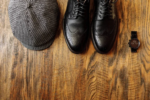 男式服装套装 配有黑色经典鞋子 手表和老式灰色帽子 独立于木制背景 顶部视图 — 图库照片