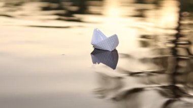 Güzel bir gün batımında kağıttan bir tekne suda yüzüyor. Origami gemisi yelken açıyor. Rüya, gelecek, çocukluk, özgürlük ya da umut kavramı. Ağır çekim. Yüksek kaliteli FullHD görüntüler.