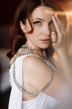 Güzellik konsepti Parlak makyajlı ve saç stili olan gösterişli, genç bir esmer kadının portresi. Sırtında değerli taşlar olan lüks elbiseli bir kız. Uluslararası Kadınlar Günü.