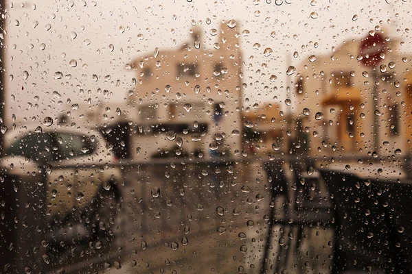 Rainy city background. Raindrops on window glass on autumn day. Wet home window with raindrops. High quality photo.