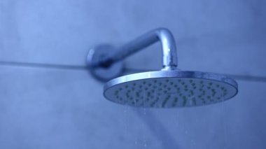 Close-up shot water drop from rain shower with dark and grain processed. Big round shower head. Jets of water flowing down. Blurred abstract close-up shot