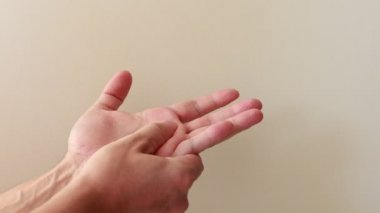 Genç erkek ellerine yaklaş, rahatlatıcı ve rahatlatıcı olmak için el masajı yap. El egzersizi, el ve el masajı, el ağrısını dindirmek için egzersiz..