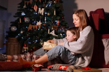 Genç anne ve kızı Noel Yıldırımı Hediyelik Kutusunu Xmas Ağacı 'nın önünde açıyor. Mutlu anne ve küçük kız Sihirli Gece 'de. Aileniz mutlu noeller ve yeni yıl tatili konsepti. Yüksek kalite fotoğraf.