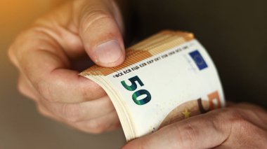 Man Counting Money. Close up of male hands counting pile of 50 euro banknotes. Euro currency exchange. Cash money calculation. Concept of salary.