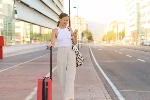 Beautiful Young Businesswoman Casual Cloth Red Suitcase Uses Smartphone Outdoors — Φωτογραφία Αρχείου