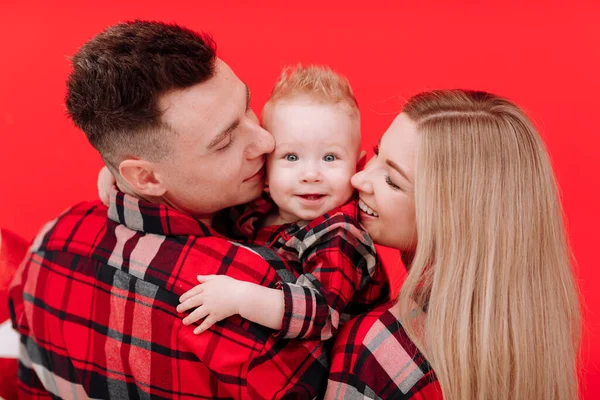 Smiling Young Mother Father Kissing Hugging Baby Boy Red Background — Stock fotografie