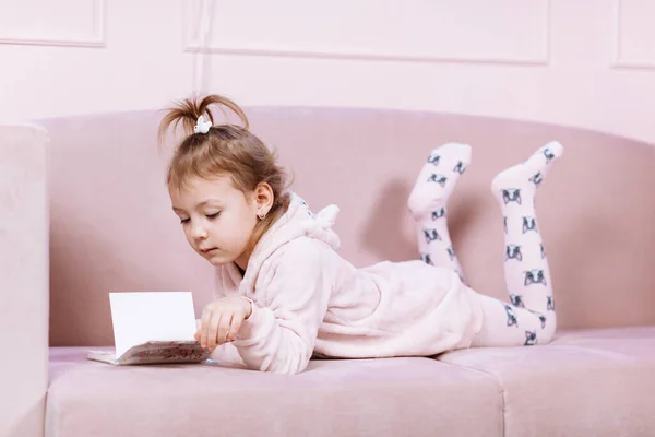 Маленькая Симпатичная Девочка Лежит Одна Розовом Диване Читает Книжку Детей — стоковое фото