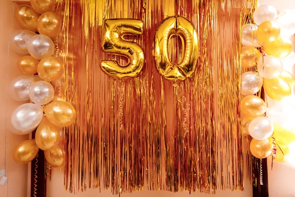 Gold foil balloon number, digit fifty. Birthday arka with gold and white balloons . Anniversary celebration event. Banner. Golden numeral, red background. Numerical digit, light bokeh, glitter