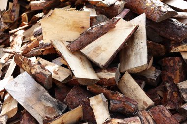 close up of pile of chopped firewood tree logs at lumber mill. Preparation for winter time. natural wood texture background. Fireplace or stove material. Timber industry concept