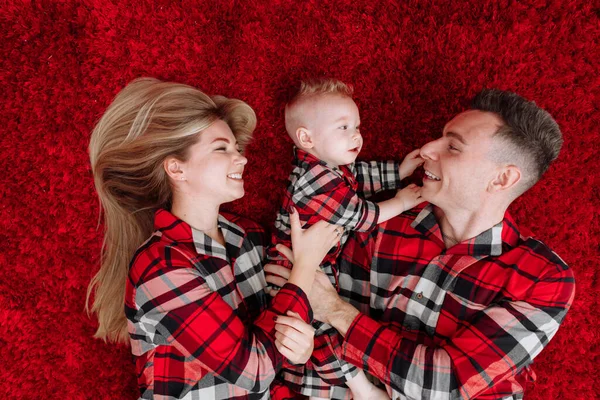 Happy Young Parents Baby Boy Same Pyjamas Lying Red Floor — Fotografia de Stock