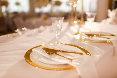 Masa örtüsü pembe masa örtüsü, mum dolu kristal şamdanlar ve restoranda beyaz pembe çiçekler. Şık bir düğün günü. Altın tepsi, çatal ve bıçaklı masa..