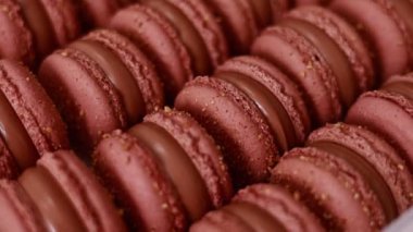 Brown sweet french macaron cakes with chocolate topping in row on the cafe display. Sets of desserts from almond dough and italy merenga in the pastry. Macaroon dessert In bakery shop