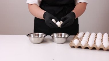 Online pişirme kursları. Bir kadın aşçı bir yumurtayı kırar ve protein sarılarını metal bir kasede krema ya da hamur hazırlamak için ayırır. Tatlı tarifleri. Aile işi. Aşçılar için çevrimiçi ders