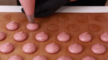 Profesyonel aşçı makaron tatlısı hazırlıyor. Kurabiye pişirmek için tepsideki boru torbasından kas kreması çıkartılan yakın plan. Pişirme, pişirme kavramı. Kapat..