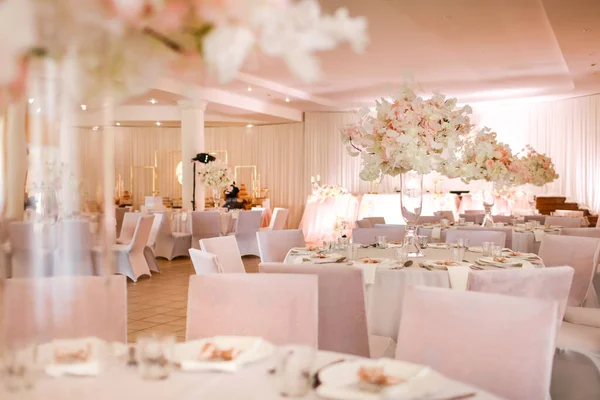 Decorated wedding banquet hall in classic style. Restaurant interior for banquet, wedding decor with white and pink flowers